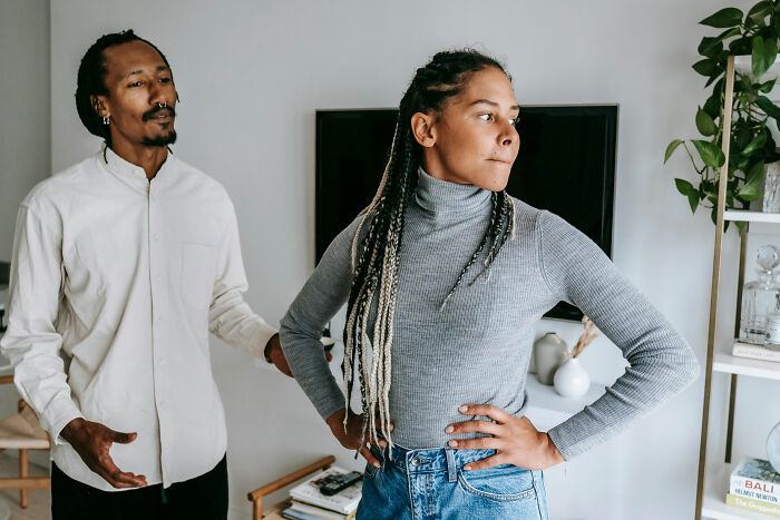 Two people discussing, conveying signs of intelligence through body language in a living room setting.
