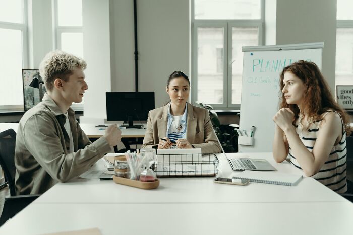 Three people engaged in a discussion, showcasing intelligence through collaboration in a modern office setting.