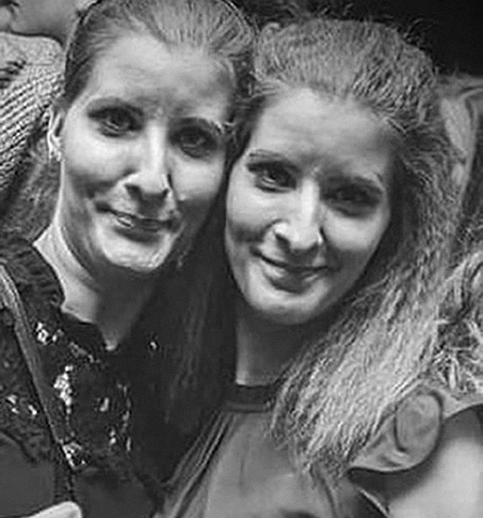 Two women standing close together, smiling, black and white photo, missing sisters theme.