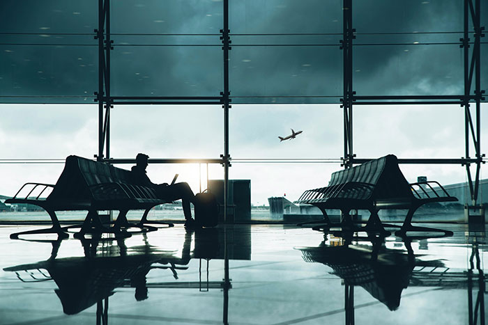 Silhouette of a person sitting in an airport terminal with a plane taking off outside. Silhouette of a person sitting in an airport terminal with a plane taking off outside.