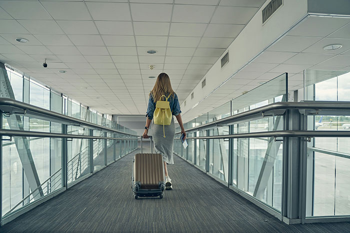 Woman with suitcase walking through airport terminal corridor. Woman with suitcase walking through airport terminal corridor.