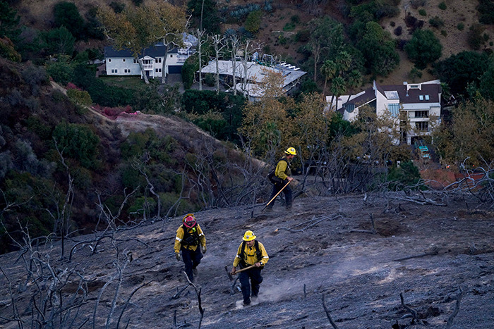 Firefighters in charred landscape near luxury homes, related to celebrities and LA wildfires. Firefighters in charred landscape near luxury homes, related to celebrities and LA wildfires.