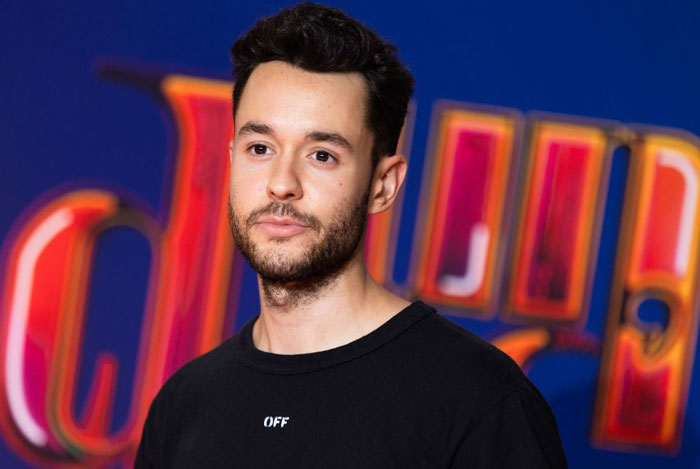 Streamer TheGrefg (David Cánovas Martínez) in a black shirt standing against a colorful background, representing famous Twitch stars.