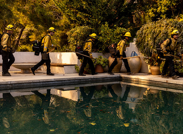 Private firefighters in yellow gear protect residential homes from wildfires, reflecting on a poolside path. Private firefighters in yellow gear protect residential homes from wildfires, reflecting on a poolside path.
