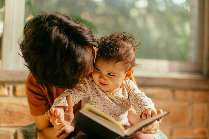 Adult and baby reading together, highlighting signs of faked maturity in parenting.