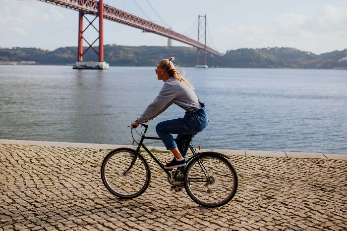 Person cycling by a river with a red bridge in the background, representing affordable ways to make life easier.