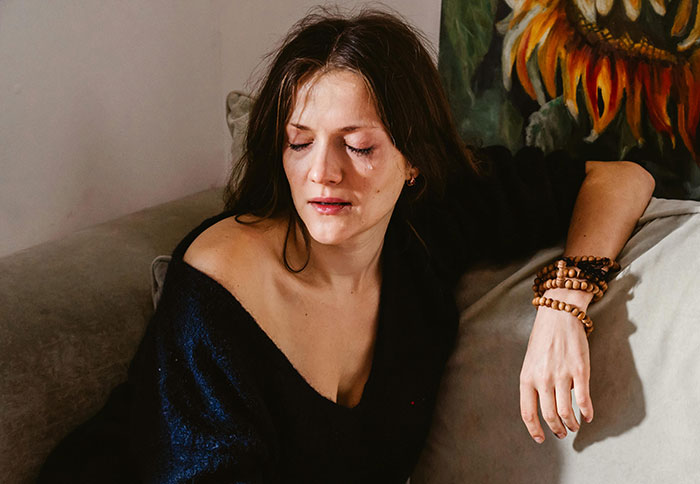 A woman looks upset on a couch, relating to a torched relationship.