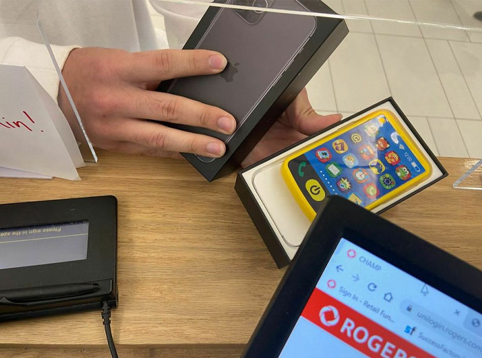 Hands holding a phone box with a toy phone inside, highlighting online shopping scams.