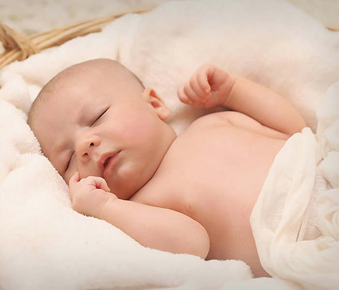 Sleeping baby wrapped in a blanket, representing Generation Beta.