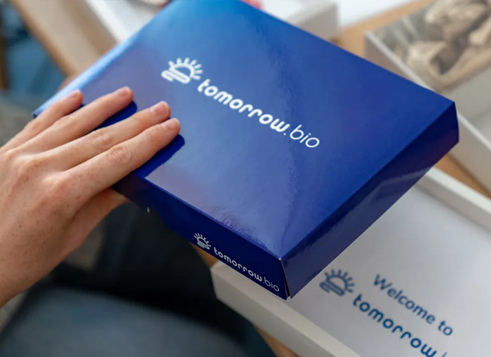 Hand touching a Tomorrow Bio box related to $200k service to freeze bodies and revive them in the future.