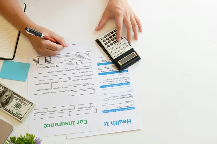 Person calculating expenses, using a calculator with documents and cash, symbolizing high-paying remote jobs.