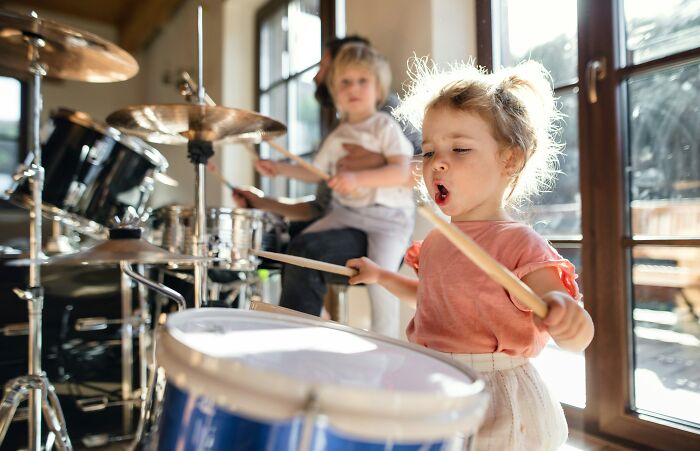 Children enthusiastically playing drums.