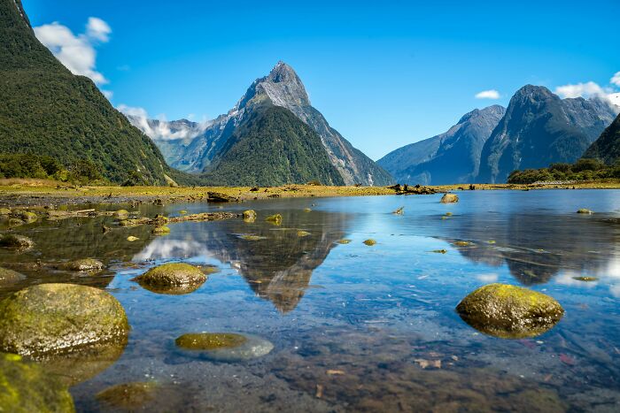 Beautiful mountain landscape in Italy's Tuscany region reflected in a serene lake under a clear blue sky.