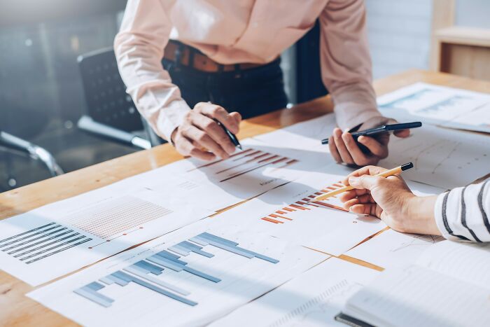 Colleagues analyzing financial graphs, highlighting strategies for high-paying remote jobs in a collaborative office setting.