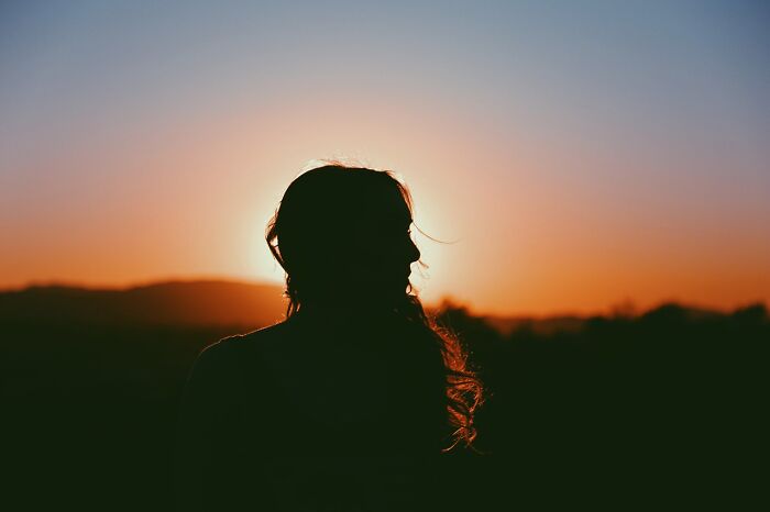 Silhouette of a person at sunset, concept of hidden celebrity profiles obscured by light.