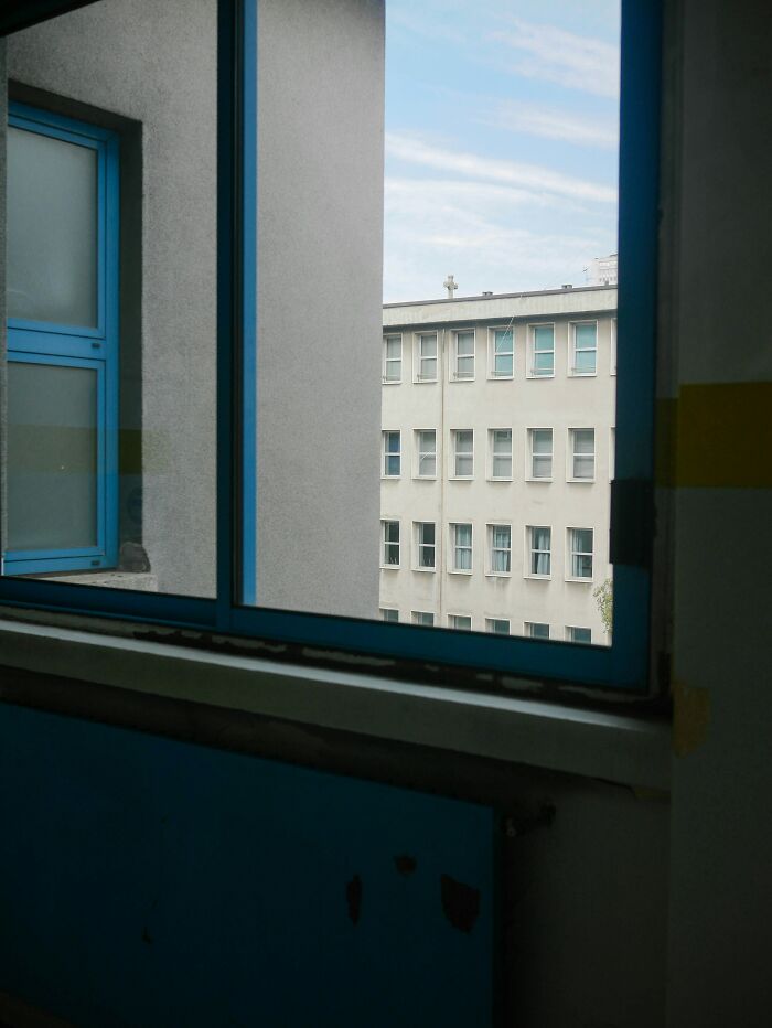 View from an open window showing a neighboring building, hinting at untold family stories.