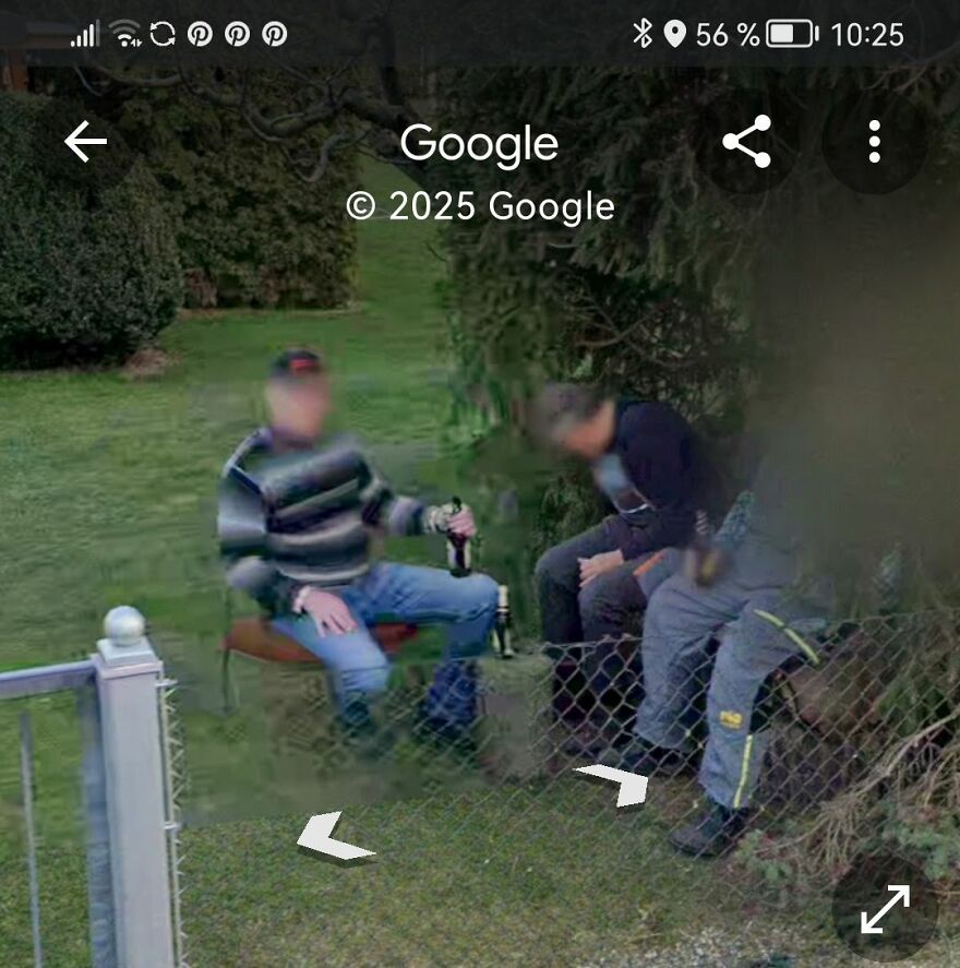 People spotted by Google Earth sitting on chairs near a fence in a garden setting.