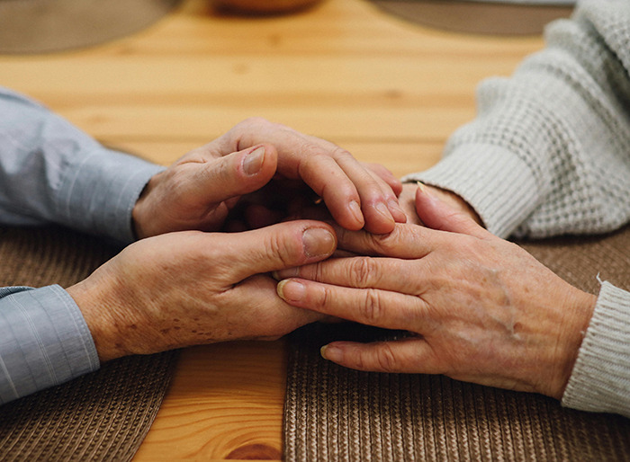 Hands holding each other on a wooden table. Hands holding each other on a wooden table.