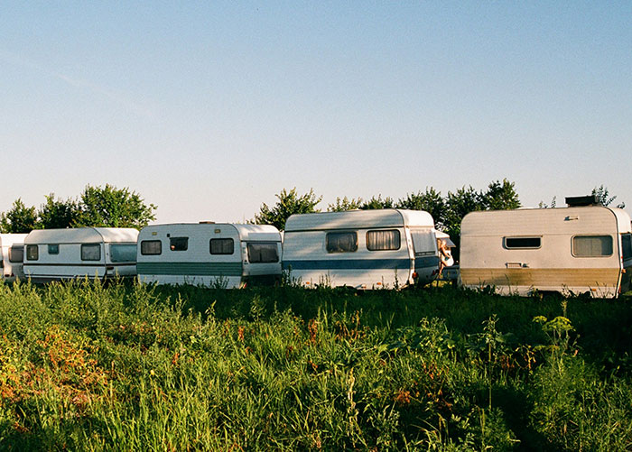 A row of caravans parked on a grassy field, representing ordinary experiences of wealthy people.