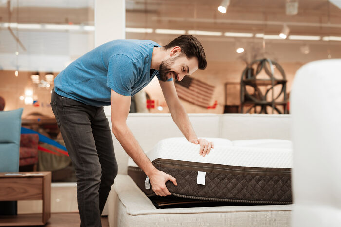 Man adjusting a mattress in a store, a purchase praised for saving time, money, and space.