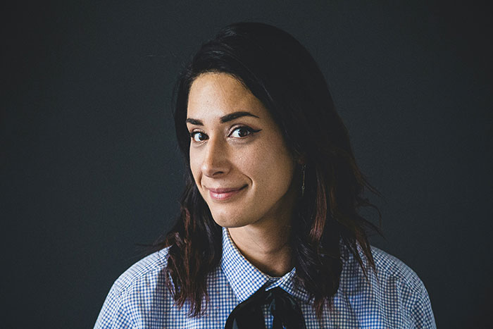 Person smiling, wearing a checkered shirt with a tie, representing life's lessons in a relaxed setting.