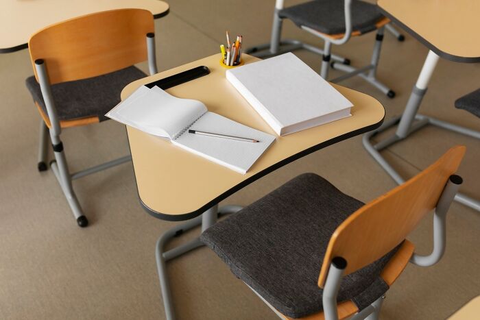 Classroom desk with books and stationery, representing teachers and school activities.