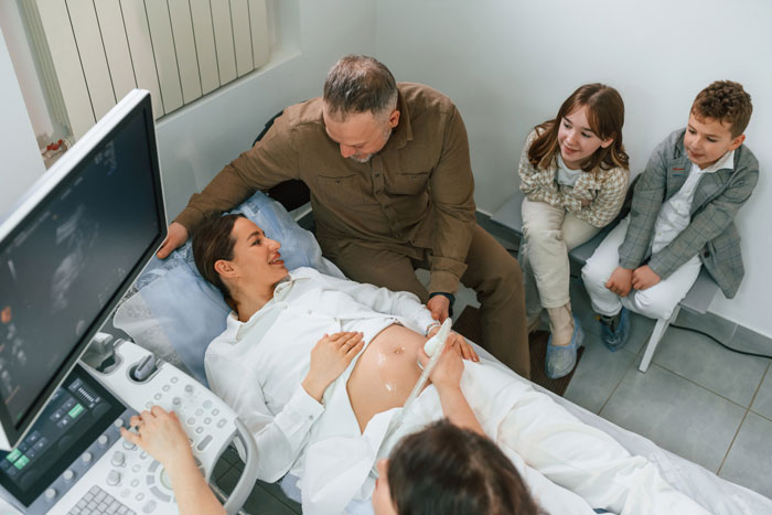 Family supports pregnant woman during ultrasound, focused on childbirth and hospital expenses.