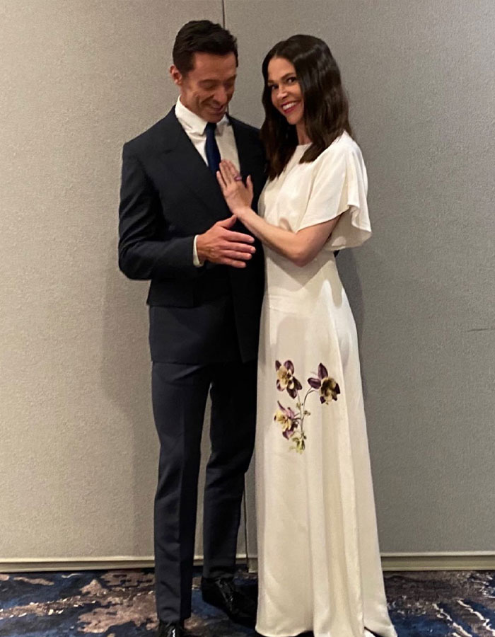A couple in formal attire posing together; she is in a floral dress and he is in a suit. A couple in formal attire posing together; she is in a floral dress and he is in a suit.