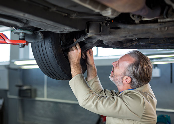 Mechanic inspects car undercarriage, illustrating vehicle issues in a story about horrible ex in a bugged car. Mechanic inspects car undercarriage, illustrating vehicle issues in a story about horrible ex in a bugged car.
