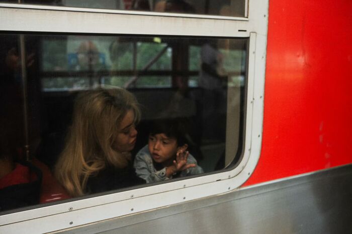 A woman and child inside a train, seen through a window, capturing a moment of street photography.