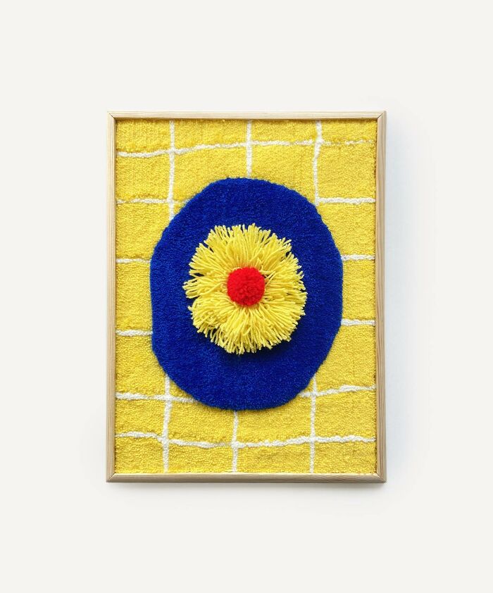 Tufted artwork featuring a vibrant yellow and blue circular design with red center on a yellow grid background.