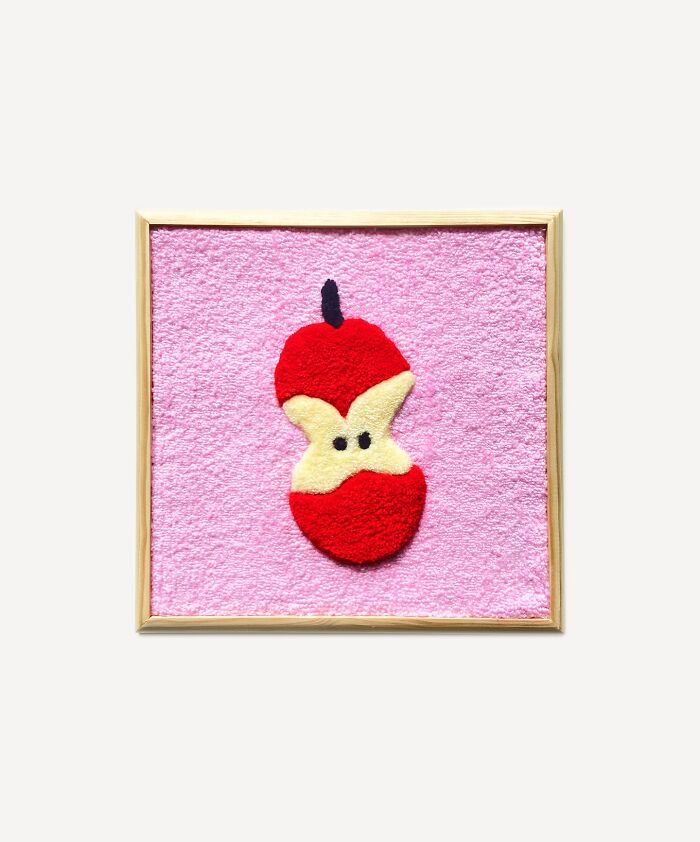 Tufted artwork featuring a stylized apple core on a pink background by Cléa Delogu.