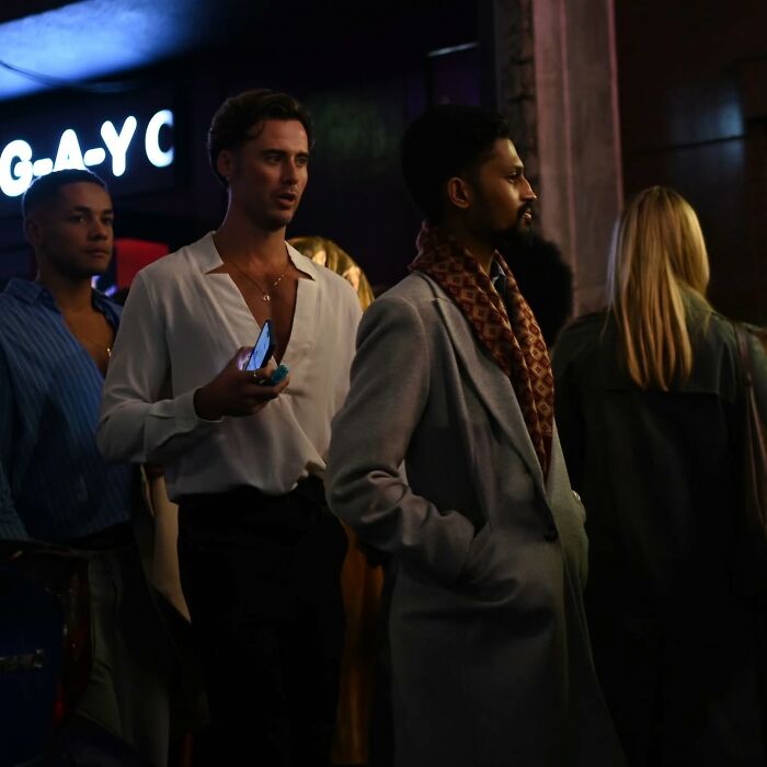 People standing in a dimly lit urban night scene, capturing street photography essence.