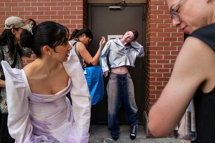 People captured in candid street photography scene against a brick wall.