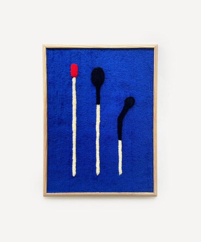 Tufted artwork by Cléa Delogu featuring three matchstick figures on blue background.