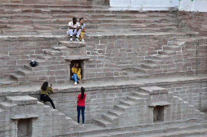 People sitting on historic stone steps, engaging with the surroundings in captivating street photography.