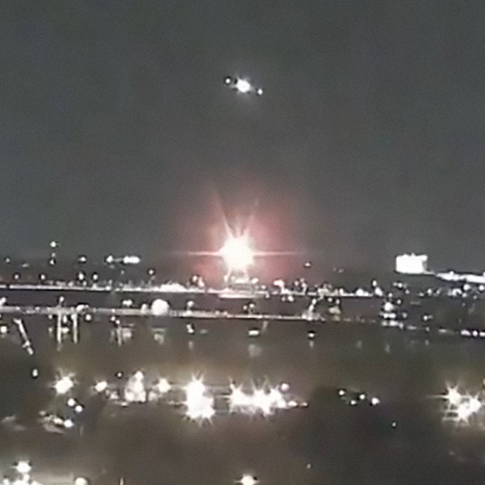 Nighttime cityscape with lights and a distant plane in the sky; bonechilling scene captured before the DC plane crash.