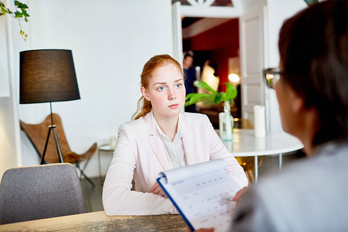Job candidate in interview, seated across from recruiter, highlighting potential employee red flags in bright office setting.