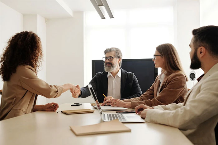 Recruiters in a meeting, discussing potential employees, with a handshake across the table in a professional setting.