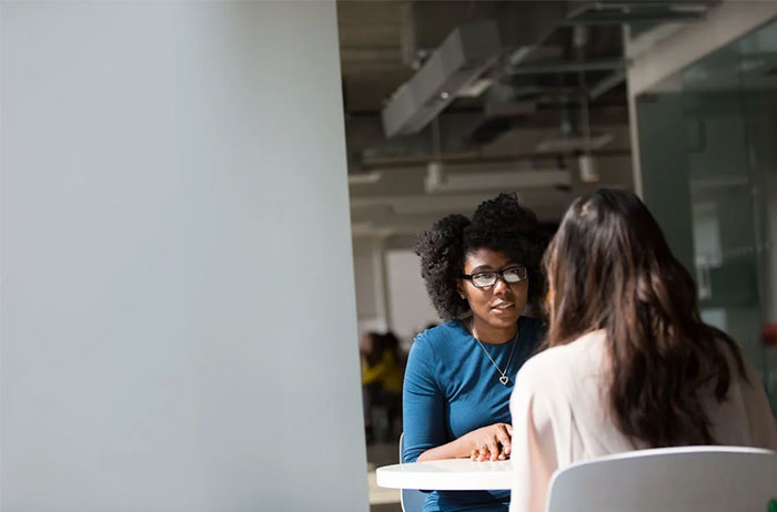 Two people having a discussion at a table with a recruiter potential employees focus.