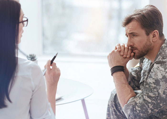 Man in military uniform in therapy session, highlighting human behavior.