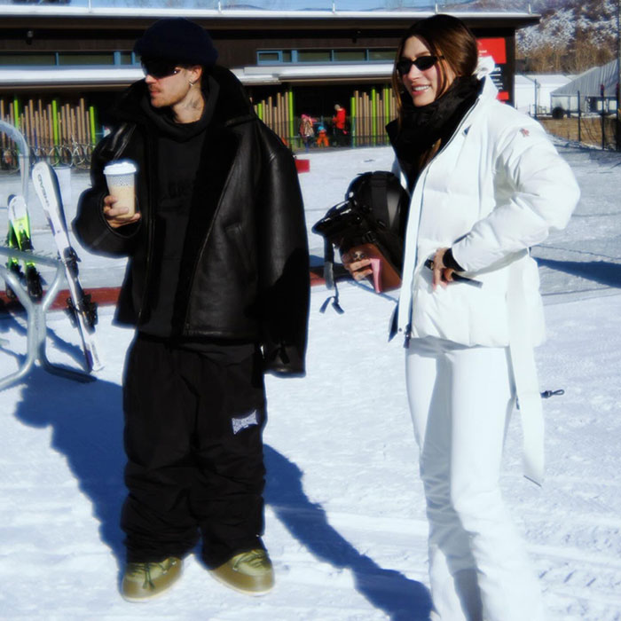 Snowy scene with Hailey Bieber in white outfit and Justin holding a coffee cup, both enjoying winter activities. Snowy scene with Hailey Bieber in white outfit and Justin holding a coffee cup, both enjoying winter activities.