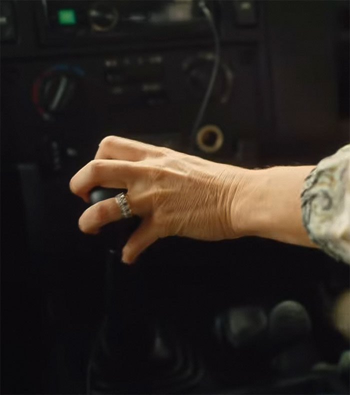 Close-up of a hand with an engagement ring on the steering wheel, sparking theories about its mystery.