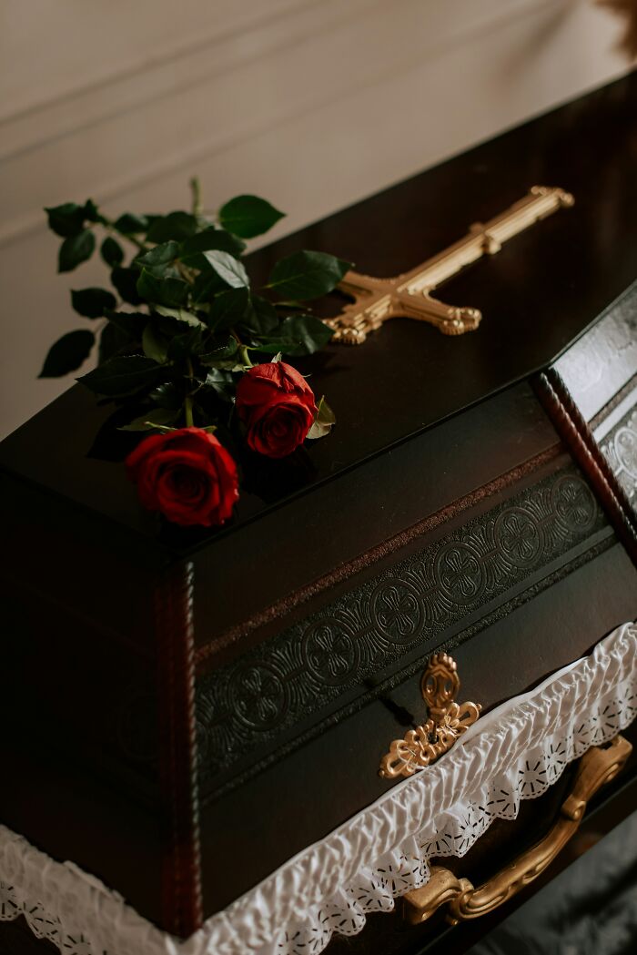 Coffin with gold cross and roses, symbolizing untold family stories.