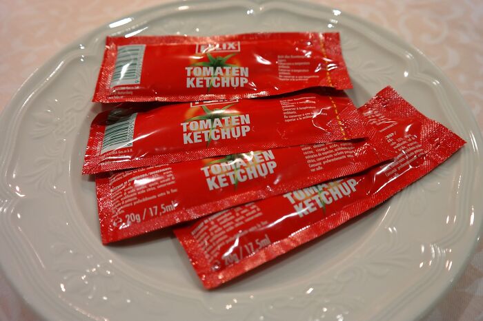 Ketchup packets on a plate, illustrating an unethical life hack for obtaining free condiments.