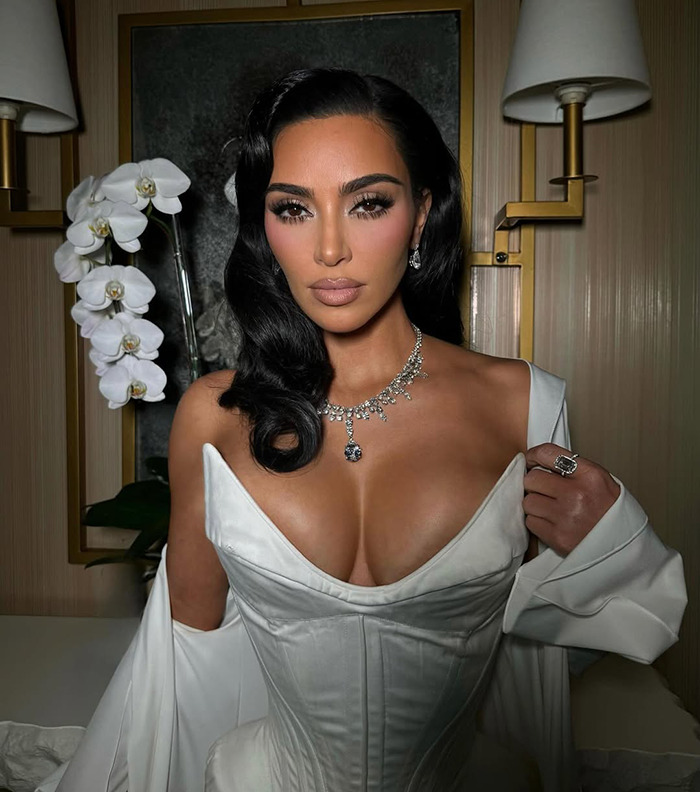 Kim Kardashian wearing a white gown and diamond jewelry in a luxurious setting. Kim Kardashian wearing a white gown and diamond jewelry in a luxurious setting.