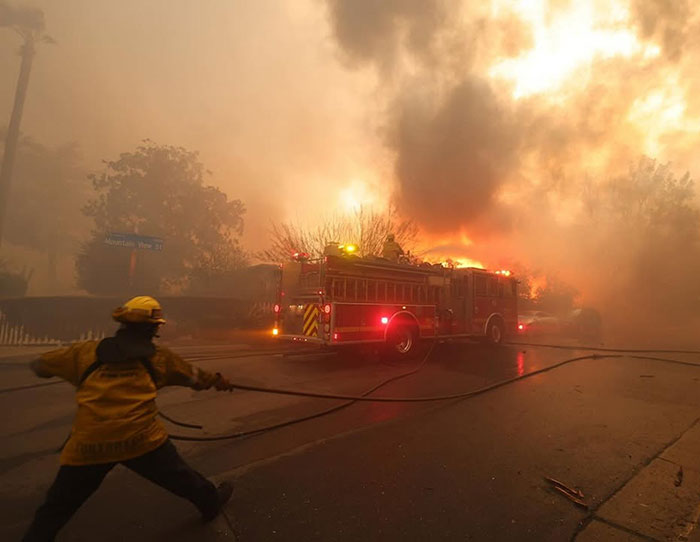 Firefighter battles intense blaze in LA, highlighting wildfire tragedy causes. Firefighter battles intense blaze in LA, highlighting wildfire tragedy causes.