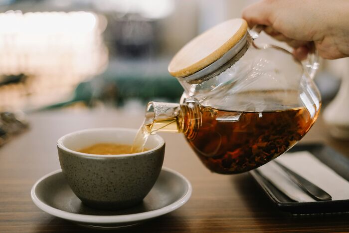 Pouring tea from a glass teapot into a ceramic cup, illustrating affordable ways to make life easier.