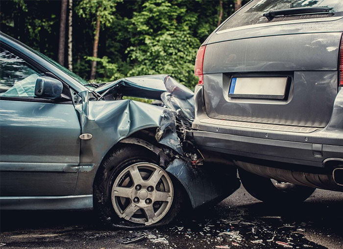 Crashed cars on a road in a forest area, symbolizing wise observations about driving safety.