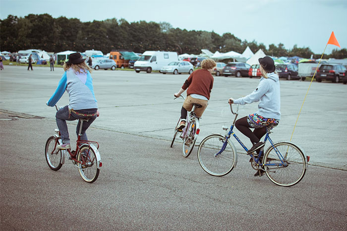 Three people riding bicycles in an open parking area, sharing wise observations and enjoying companionship.